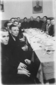 Grupa os&oacute;b przy zastawionym stole.