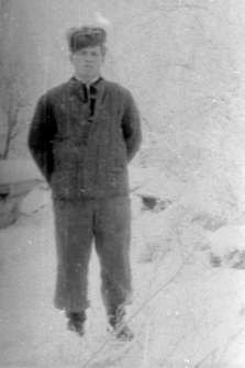 Mężczyzna w kufajce na tle zimowego krajobrazu.