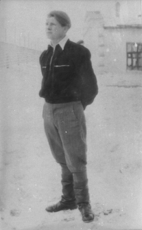 Mężczyzna w swetrze na tle budynku.