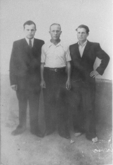 Trzech mężczyzn, jeden w garniturze pod krawatem.