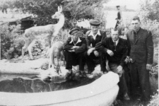 Czterech mężczyzn przy fontannie z sarenkami.