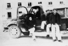 Mężczyźni przy ciężarówce na tle budynku.