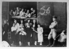 Transport więźniów z łagru w Dżezkazganie do łagru w Bałchaszu - grupa mężczyzn i kobiet przy wagonie kolejowym, obok stoi żołnierz.
