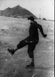 Stanisław Kiałka po zwolnieniu z łagru. Mężczyzna w czapce-uszance jeździ na łyżwach. W tle hałda kopalni 9-10. Zdjęcie z 1955-56 roku.