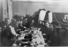 Moment pożegnania przed odjazdem grupy Polaków do kraju. Grupa osób przy stole, trzeci od lewej Mikołaj Cichanowicz.
