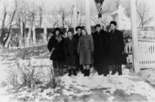Grupa ludzi w zimowych ubraniach na tle zimowego krajobrazu.