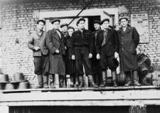 Grupa mężczyzn w strojach roboczych przed magazynem kopalni Miedwieżyj Ruczaj, drugi od prawej: Romuald Raubo.