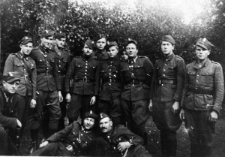 Upozowana grupa mężczyzn w mundurach, na tle lasu.