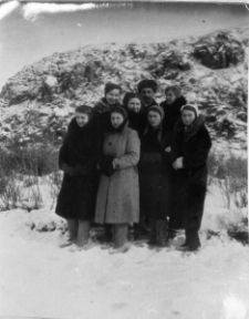 Grupa osób w strojach zimowych na tle zimowego krajobrazu.