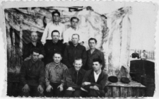 Grupa mężczyzn na tle malowanych dekoracji (?). Polacy, więźniowie łagr&oacute;w. Od lewej, dolny rząd: NN, Kazimierz Babicz, NN, NN; rząd środkowy: NN, Stanisław Bohdziewicz, Wincenty (nazwisko nieznane), NN; rząd g&oacute;rny: nierozpoznani.