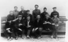 Robotnicy w kopalni "Miedwieżyj Ruczaj". Grupa mężczyzn siedzących na stosie desek (?). Trzeci od lewej w pierwszym rzędzie: Stanisław Mogielnicki, pozostałe osoby nierozpoznane.
