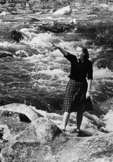 Janina Durlik - stoi nad brzegiem rzeki na tle wzburzonej wody...