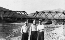 Trzech mężczyzn w koszulach na tle mostu nad rzeką.