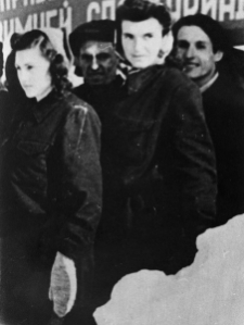 Dwie kobiety na czele większej grupy ludzi pod nieczytelnym transparentem.