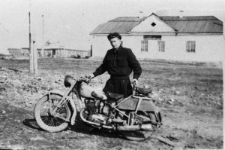 Eugeniusz Cydzik i motocykl, w tle budynek.