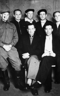 Siedmiu mężczyzn upozowanych we wnętrzu. Od lewej trzeci, u g&oacute;ry w czapce - Chodar.