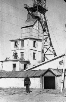 Mężczyzna w stroju g&oacute;rnika na tle wyciągu kopalni (?).
