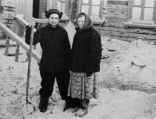 Mężczyna i kobieta w waciakach przy wejściu do drewnianego domku.