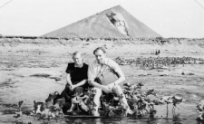 Mężczyzna i kobieta siedzący w płytkim rozlewisku. W tle góra.