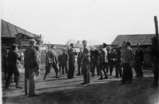 Grupa wojskowych i cywil&oacute;w podczas meczu piłki siatkowej (piłka wysoko w g&oacute;rze).