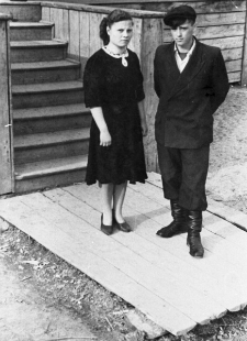 Mężczyzna i kobieta przed wejściem do drewnianego domu. Tadeusz Skraba i Rosjanka (imię i nazwisko nieznane). Fotografia wykonana prawdopodobnie w latach 50-tych.