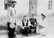 Czworo ludzi przed budynkiem, jeden w mundurze Armii Czerwonej.