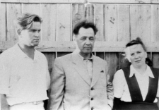 Kobieta i dw&oacute;ch mężczyzn na tle drewnianej ściany.