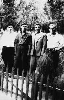 Czterech mężczyzn na tle drzew, za drewnianym płotkiem. Więźniowie łagru; drugi od lewej: Romuald Kononowicz, czwarty: Polak (nazwisko nieznane), pozostali Ukraińcy. Podpis na odwrocie: "Na przepustce z kolegami".