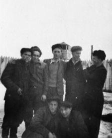 Grupa mężczyzn. Drugi od prawej: Stanisław Kowalewski, pozostałe osoby nierozpoznane. W tle ogrodzenie.