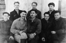Grupa mężczyzn na tle drewnianej ściany. Drugi od lewej: Stanisław Niedźwiecki, Dorożko (który?), pozostali nierozpoznani. Wigilia prawdopodobnie 1954 roku.