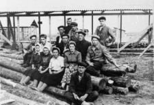 Brygada budowlana zesłańc&oacute;w z Kołomyi. Grupa mężczyzn i kobiet siedzących na balach. Na g&oacute;rze w środku: Bolesław Kratus.