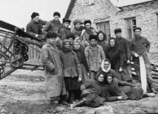 Na przymusowej zsyłce, m.in. Bolesław Kratus. Grupa ludzi w strojach roboczych. W tle murowany budynek. Podpis na odwrocie: "Na pamiątkę Najukochańszej Mateczce posyłam podobiznę z dalekiej Karagandy i proszę nie zapominać o mnie [podpis nieczytelny]".