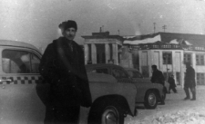 Wiktor Jagoda - na tle samochod&oacute;w osobowych i reprezentacyjnego budynku.