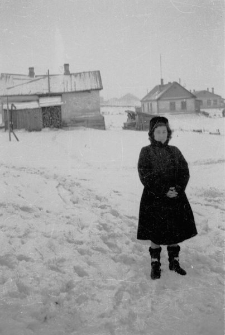 Kobieta na tle baraków dawnego łagru.