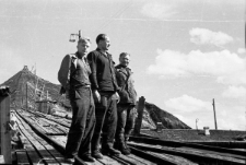 Trzej mężczyźni na tle hałdy kopalni.