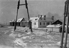 Fragment miasta, zabudowania sąsiadujące z obozem, z lewej strony widoczne ogrodzenie z drutu.