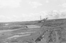 Fragment panoramy Workuty. W górnej części nad rzeką widać elektrownię (TEC-1), która zaopatrywała w elektryczność cały obszar. Po prawej stronie rozciągają się peryferie miasta, na pierwszym planie widoczne są baraki obozu przy kopalni nr 9-10, liczącej w tamtym czasie ponad 10 tysięcy więźniów".