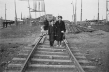 Kobieta z chłopcem na torach kolejowych, z lewej płot z żerdzi chroniący przed nawiewaniem śniegu.
