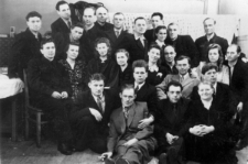 Polacy, byli więźniowie łagr&oacute;w na zesłaniu. Cztery osoby w pierwszym rzędzie na podłodze - drugi od lewej (w jaśniejszym garniturze) Edward bądź J&oacute;zef (w zależności od źr&oacute;dła, nazwisko nieznane), Stanisław Pszcz&oacute;łkowski i Rosjanka (żona jednego z Polak&oacute;w); w drugim rzędzie Kazimierz Szyłobryt (z lewej), Karol Gonet (centralnie) i Franciszek Czarkowski; rząd trzeci - osoby siedzące na krzesłach, z lewej: Edward Jackiewicz (prawdopodobnie), Aniela Kubiak, Hanna G&oacute;rska, Helena Stańczyk, Hanna Czarnocka, Zygmunt Czarnocki, Zuzanna Raubo, Romuald Raubo; stoją od lewej: Kazimierz Bujko, J&oacute;zef W&oacute;jcik, NN (mężczyzna nachylony nad Anielą Kubiak), Kazimierz Pocześniak, NN, NN, NN, NN, Stanisława Kowalewicz-Dowgiałło i Marian Dowgiałło, Jan Lebiedź.