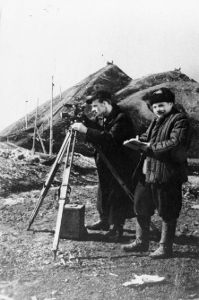 Olgierd Zarzycki, Władysław (nazwisko nieznane) przy niwelatorze (dwóch mężczyzn w strojach roboczych przy przyrządzie pomiarowym, na tle krajobrazu).