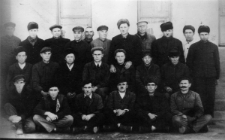 Duża grupa mężczyzn na tle budynku. Więźniowie (brygada) łagru: drugi od lewej w środkowym rzędzie: Józef Czebotar, pozostałe osoby nieznane; zdjęcie z 1955-56 roku.