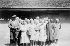Obóz żeński St. Tajga, kaflarnia (?). Grupa kobiet w fartuchach, w pierwszym rzędzie rosły mężczyzna. W tle budynek. Fotografia znaleziona przez miejscowego rybaka na miejscu obozu nad jez. Onega, zlikwidowanego w 1941 roku, ofiarowana Renardowi Bronisławowi Michalskiemu. Zdjęcie z 1939 lub 1940 roku.