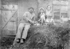 Rodzina polska na zesłaniu. Rodzice z dzieckiem siedzą na kupie siana przed drewnianą chałupą - Elwira Adamczewska z matką i ojcem w kołchozie "Żyzń i Trud" poczta Bujdajewska, Kuznieckij rejon, Kiemierowskaja obłast.