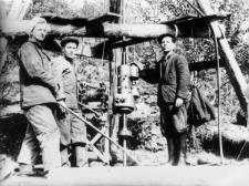 Zesłańcy zatrudnieni w kopalni złota przy maszynie wiertniczej poszukującej złóż. Trzy osoby w strojach roboczych przy maszynie. Od prawej: majster Ukrainiec (zesłaniec), Ukrainiec, Jadwiga Borodziuk.