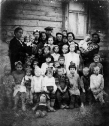 Opiekunowie i wychowankowie polskiego przedszkola, stoją od lewej: Julia Lampart, Aniela Cisek z Janiną Nogą na ręku, dziewczynka NN, Bronisława Wawryk, Emilia Bajorek, starsza kobieta przy oknie to Waleria Bajorek, obok z lewej jej syn Roman, przed nim stoi Janina Kołodziej, za dziewczynką NN w białej sukience i z kokardą we włosach stoi Stanisław Domański, w grupie dzieci na dole druga od lewej siedzi Kazia [nazwisko nieznane], trzecia Bronisława Cisek, chłopiec czwarty z prawej to Stefan Topolewski, przed dziećmi na ziemi siedzi Kundzia, szmaciana lalka Bronisławy Cisek z darów amerykańskich.