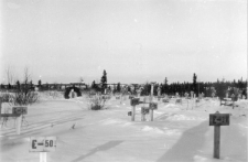 Cmentarz łagru przesyłowego OŁP-5, w tle obozowe baraki.