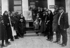Grupa osób przed Zarządem Gminy, w środku stoi portret Józefa Piłsudskiego.