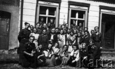 Grupa młodzieży oraz kilku wojskowych przed budynkiem, prawdopodobnie II wojna światowa.