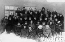 Pożegnanie Drzewickiej i Urbanowskiej wyjeżdżających do Kujbyszewa. Pierwszy rząd na śniegu: Kowalski, Edward Kulczycki (w okularach), Ewa Najwer (w białej kapuzie), Andrzej Wandurski (w pilotce). Drugi rząd w śniegu: Gawlikowska, NN, Lusia Piętnicka, Adaś Zyga, Krysia Zyga i Jurek Gawlikowski. Siedzą od lewej: NN, Paulina Piętnicka, Jacyszynowa, Janina Kaczorowska, NN, Leopoldyna Urbanowska, Helena Drzewicka, Maria Płaza. Wyżej stoją: Irka Jacyszyn, Zofia Wandurska, NN, Aniela Najwer (w chuście), NN, Zygowa (w berecie). W ostatnim rzędzie Musia Piętnicka, NN, NN, Kobylecka, NN, Kobylecki, NN, NN. Zdjęcie wykonane przed barakiem 13 w "Centrali" mołotowskiego sowchozu.