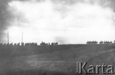 Maszerujący żołnierze. Ciemne konne i piesze postacie na horyzoncie na tle jasnego nieba.